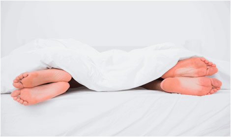 image of a couple sleeping together with feet sticking our from under the comforter